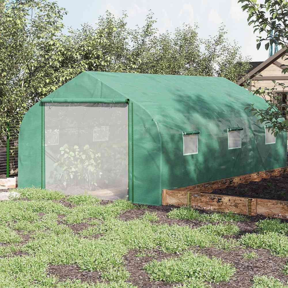 Serre verte avec plantes près d’un potager