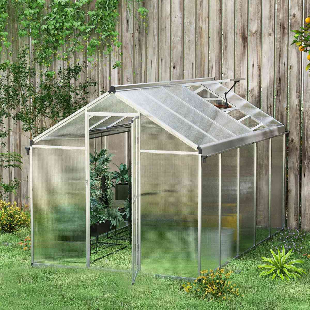 Serre en polycarbonate installée près d’une clôture en bois