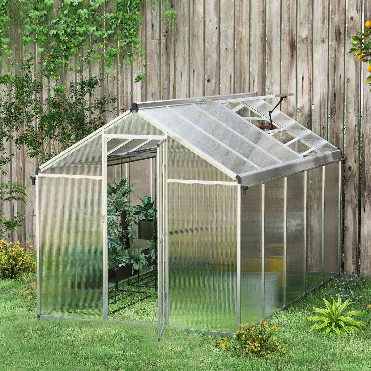 Serre en polycarbonate installée près d’une clôture en bois