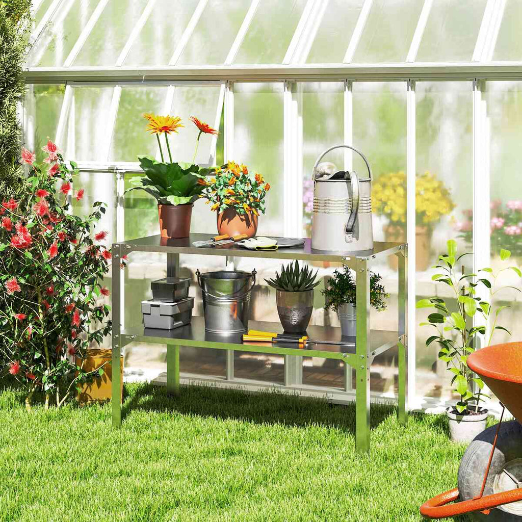Table de rempotage avec plantes en pots et arrosoir à l’intérieur d’une serre