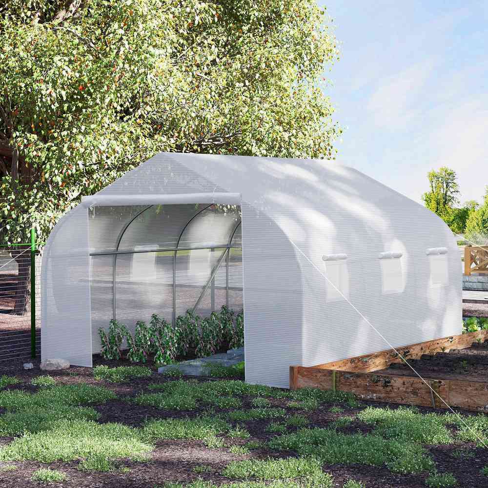 Serre tunnel blanche au jardin avec plantes devant l’entrée