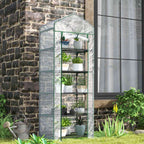 Mini serre blanche avec plantes près d’un mur en pierres