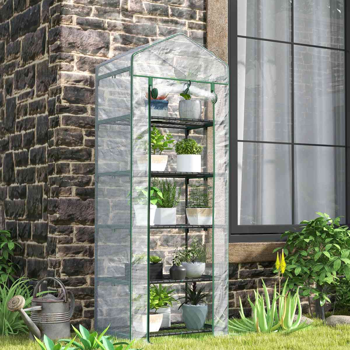 Mini serre blanche avec plantes près d’un mur en pierres
